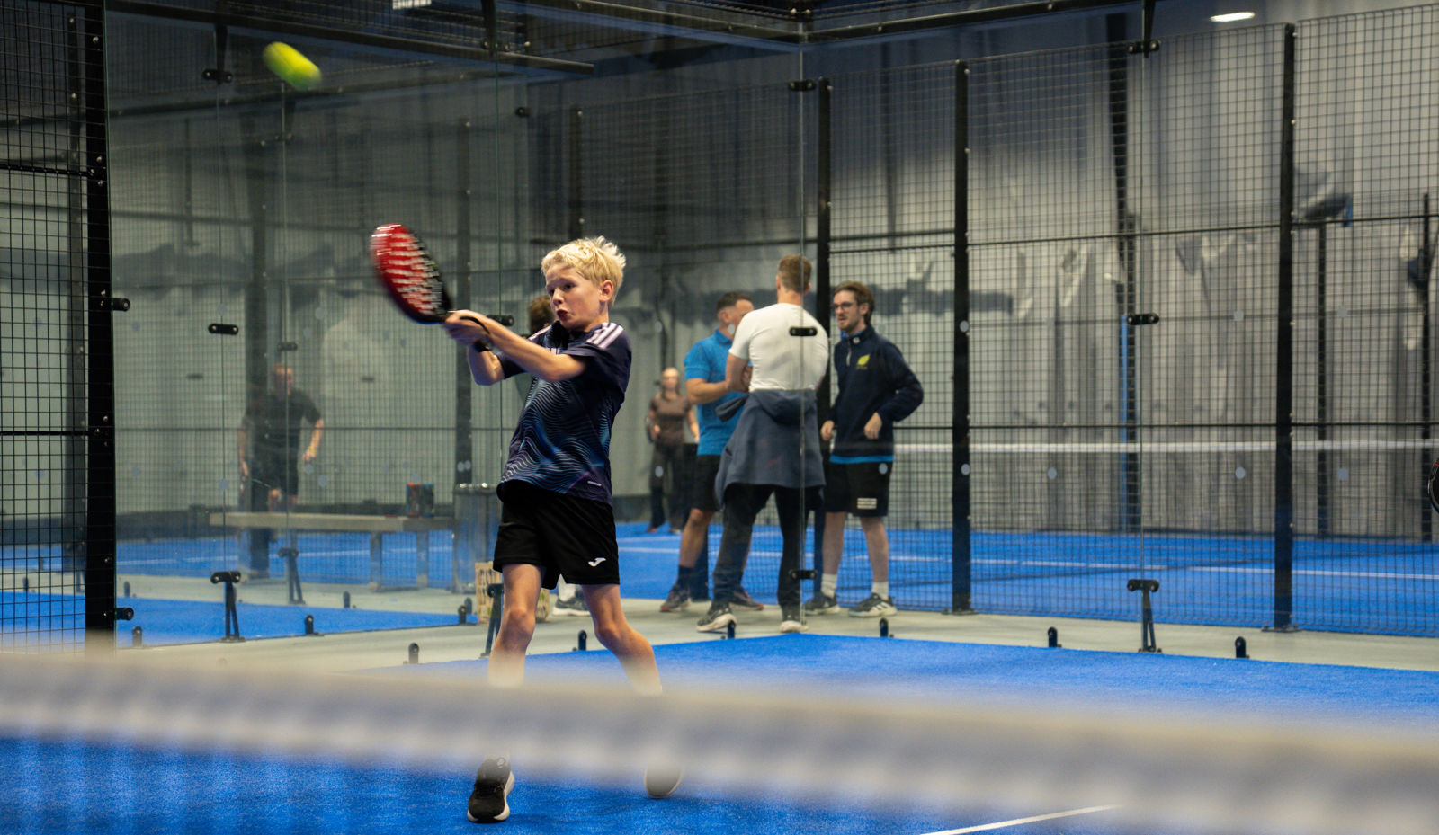Players mid-rally on the indoor courts at Les Ormes Padel in St Brelade, Jersey